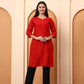 Woman wearing a red kurta with black pants standing in front of beige arches.