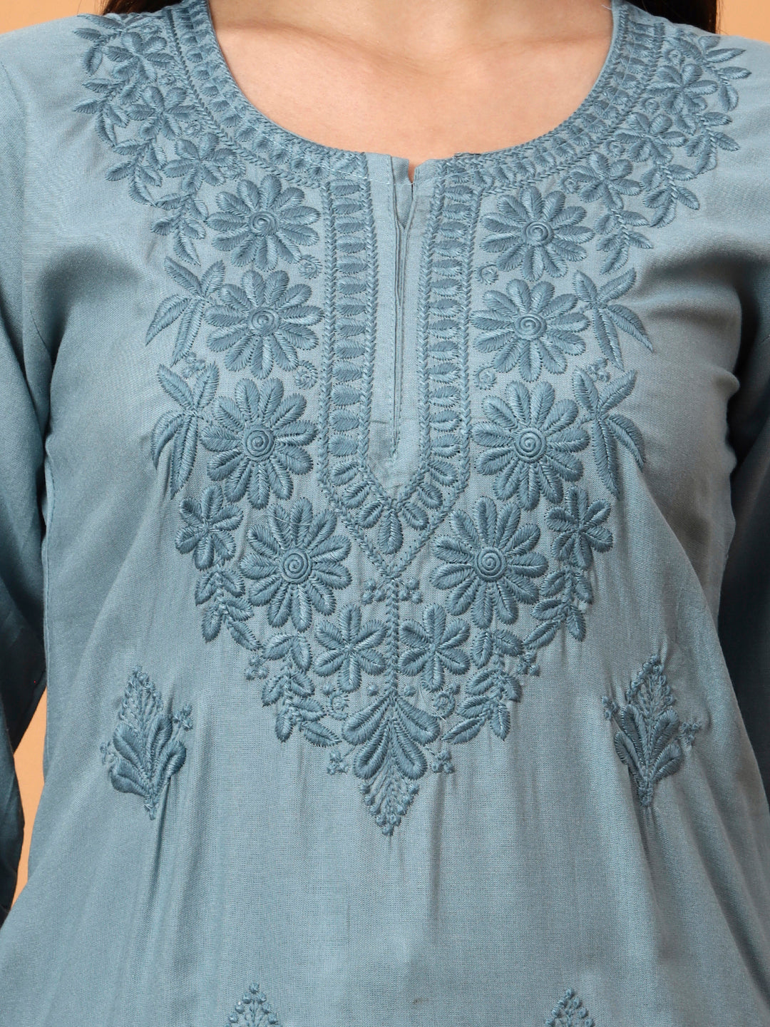 Close-up of a light Green embroidered garment with floral patterns.